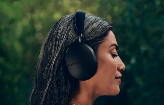 Woman wearing black Sonos Ace wireless over-ear headphones outdoors